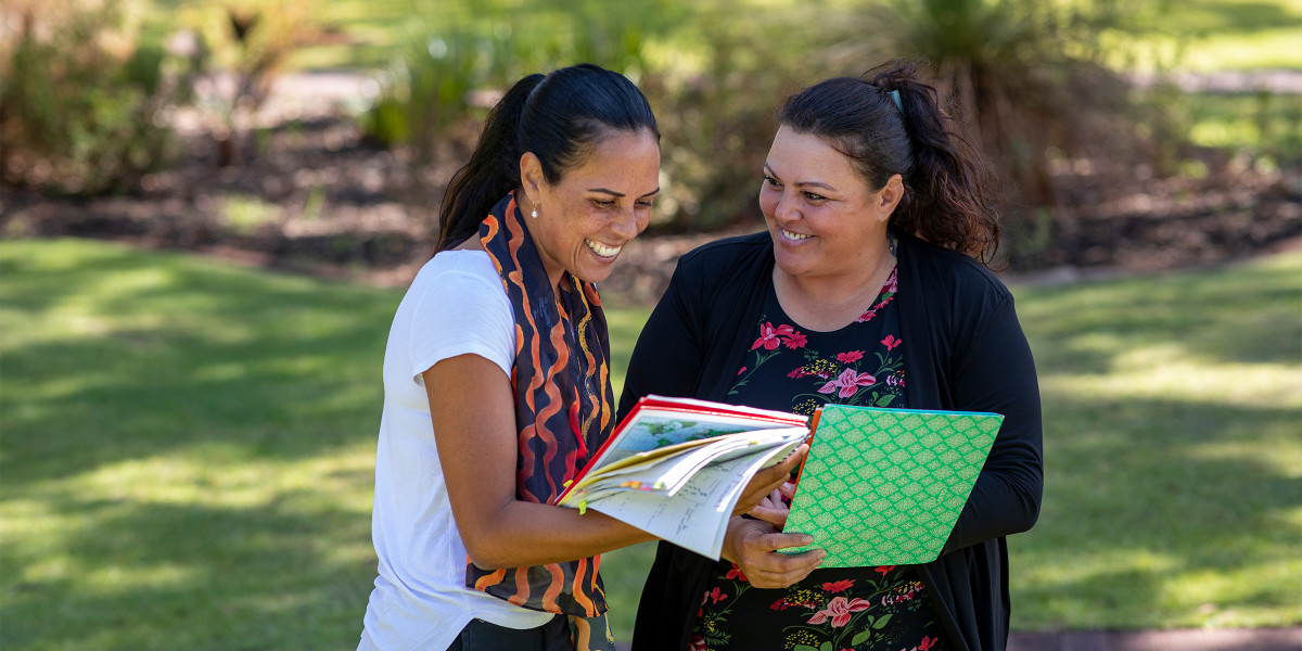 Two people looking at a notebook and smiling