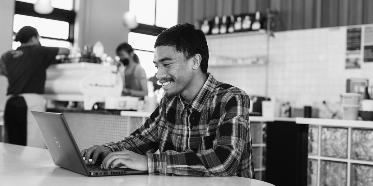 Man sitting in a cafe typing on a laptop